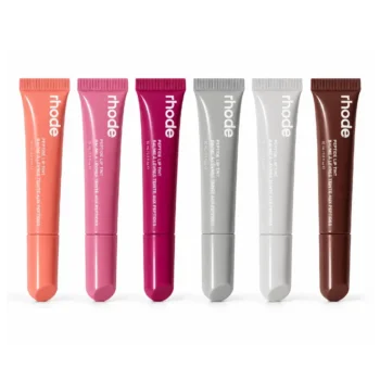 Home 29 Six tubes of Rhode Peptide Lip Tint and Lip Treatments arranged vertically side by side in shades ranging from sheer pink and berry to grey packaging and deep espresso brown